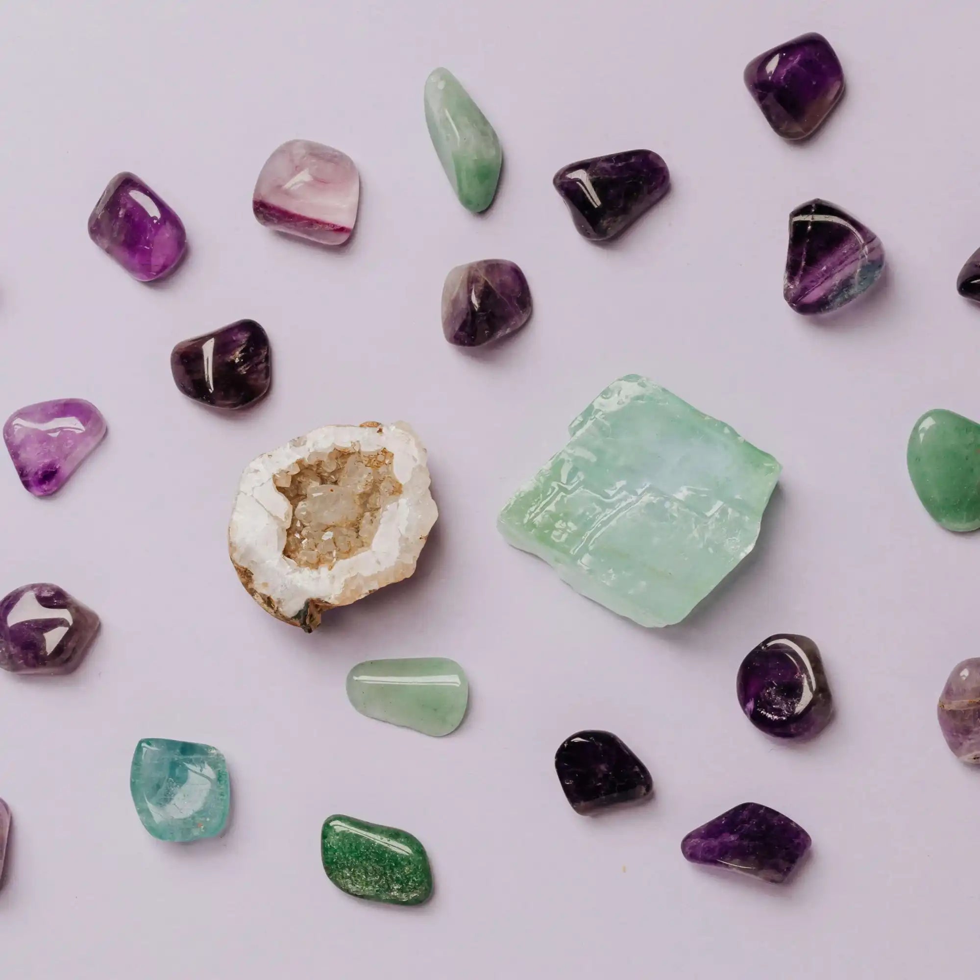 Collection of polished crystals and gemstones in purple and green hues.