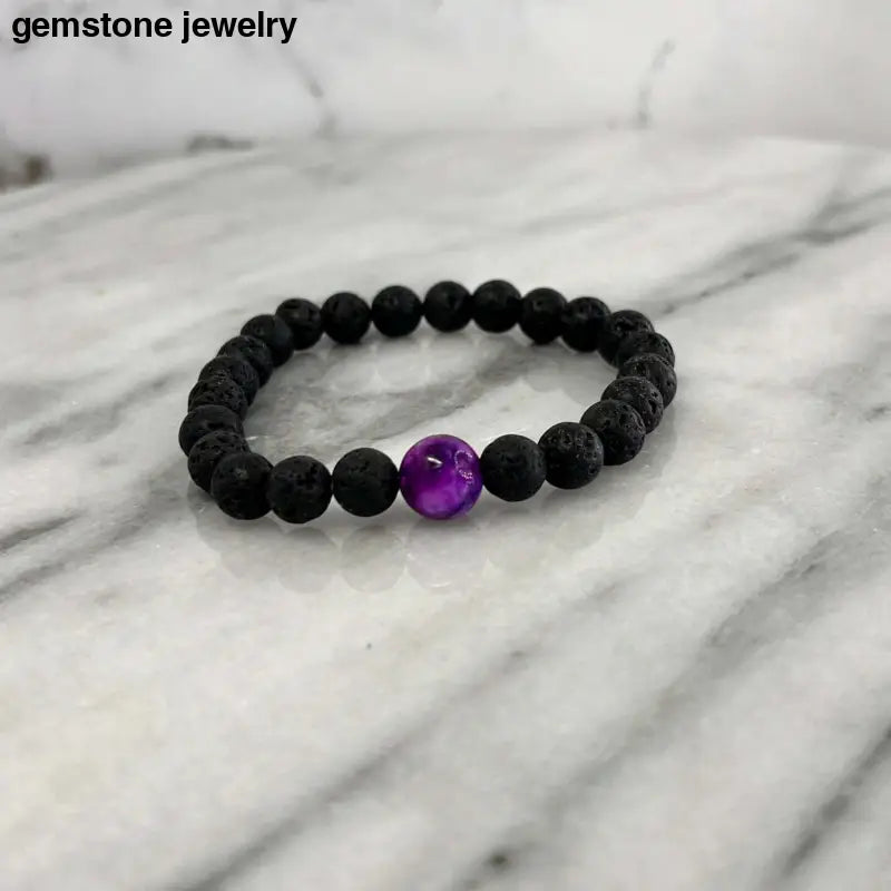 Lava rock bracelet and sugilite diffuser bracelet on marble surface for aromatherapy and wellness.