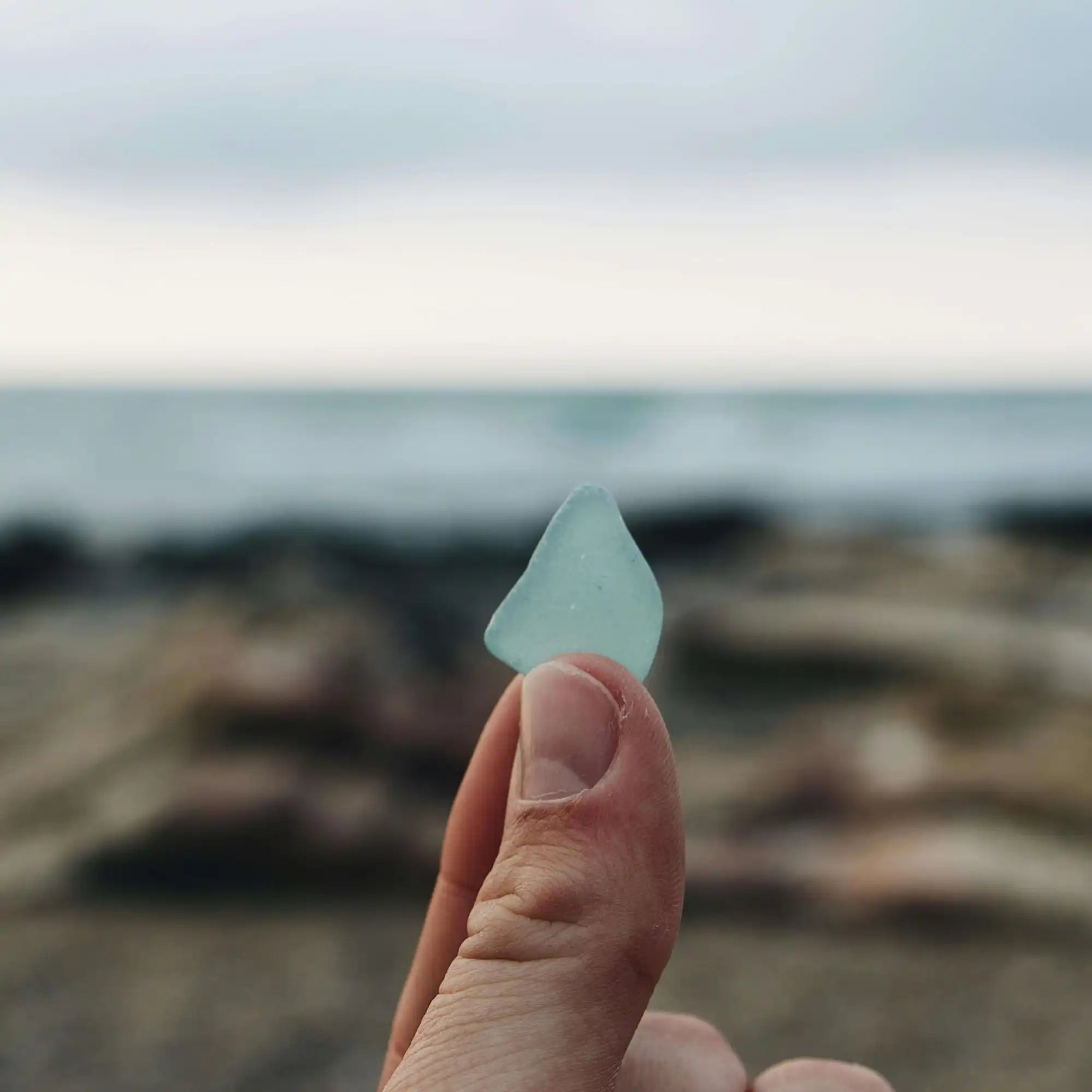 A piece of sea glass held between fingers.